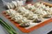 a tray of dumplings on a mat with green onions