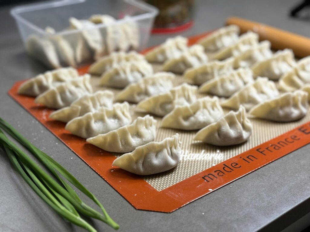 a tray of dumplings on a mat with green onions