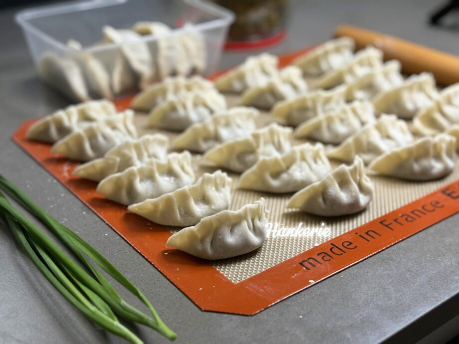 a tray of dumplings on a mat with green onions